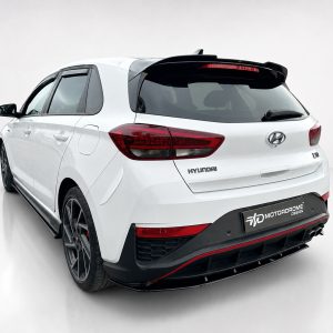 Rear-left view of a white Hyundai SUV with red taillights, Hyundai badge, and a black rear bumper featuring a Motordrome plate graphics.