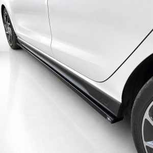 White car side view showing a black side skirt and alloy wheel at the rear area