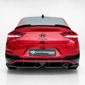 Rear view of a red Hyundai Fastback in a studio setting, showing taillights, spoiler, and a Motordrome Design plate.