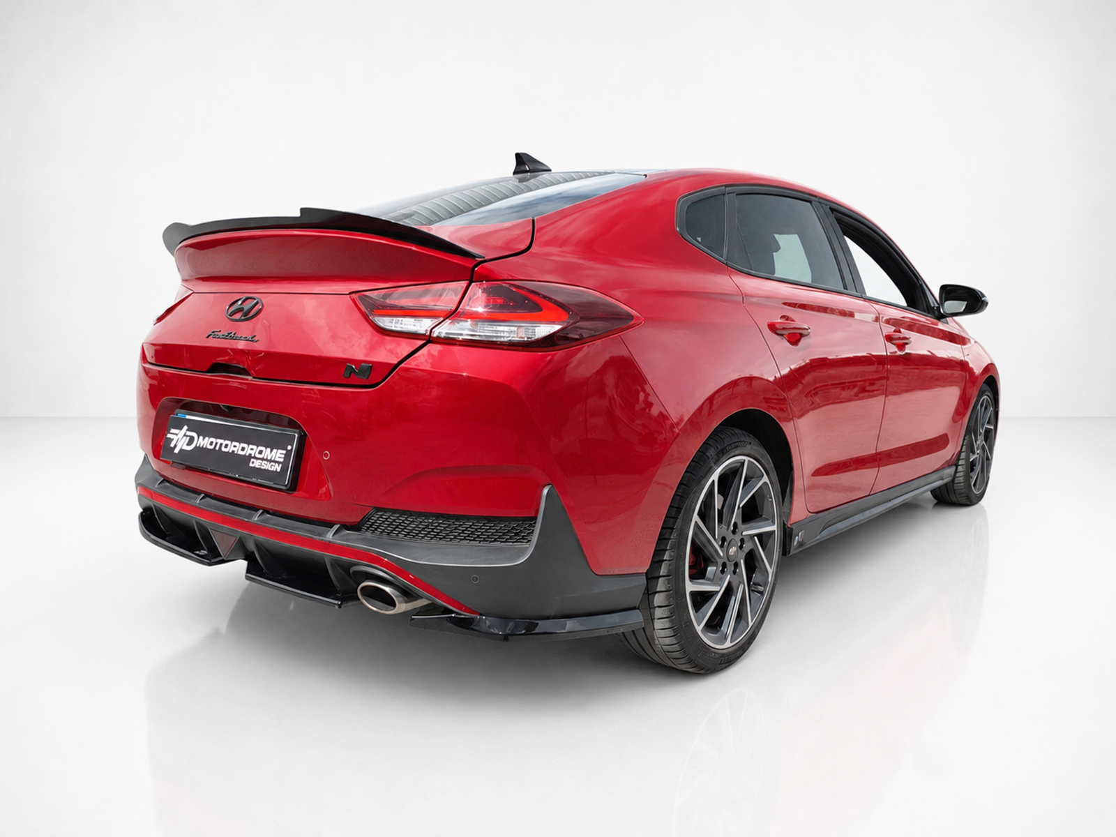 K180-005_2jpg - OPSHOLDERS Red Hyundai sedan viewed from rear-right in a studio setup, featuring a spoiler and sporty black rear bumper accents.