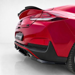 K180-005_3jpg - OPSHOLDERS Rear three-quarter view of a glossy red sports car showing the taillight, exhaust, and wide rear wheel in a showroom setting.