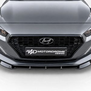 Front view of a metallic gray Hyundai with a black honeycomb grille and a Motordrome Design plate on the bumper.