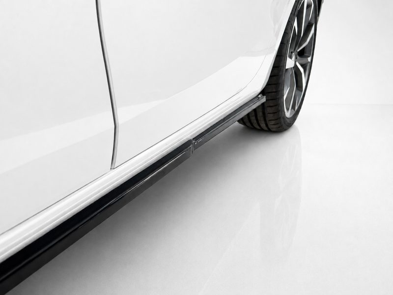 Close-up of a white car's side panel with a black running board and a tire visible at the rear site edge.