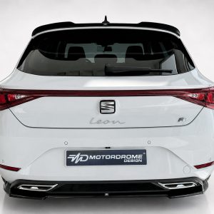 Rear view of a white SEAT Leon FR hatchback with a black roof spoiler and red taillights, showing the Motordrome Design plate on the bumper