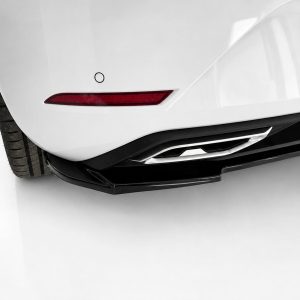 Close-up of a white car's rear bumper showing a red taillight, exhaust outlet, and diffuser details.