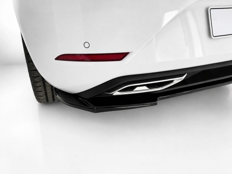 Close-up of a white car's rear bumper showing a red taillight, exhaust outlet, and diffuser details.