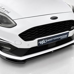 K182-001_3jpg - OPSHOLDERS Close-up of a white Ford front end showing the diamond grille, headlight, and ST-Line badge with a MotorDrome plate below.