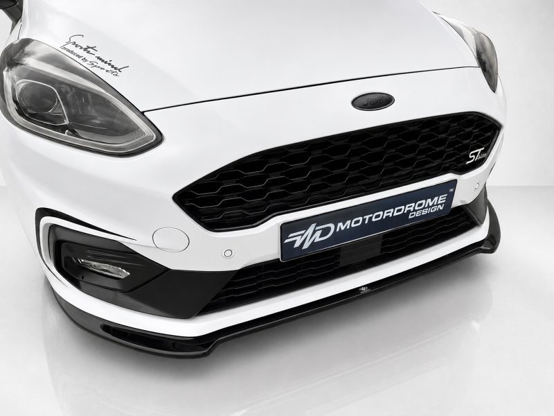 K182-001_3jpg - OPSHOLDERS Close-up of a white Ford front end showing the diamond grille, headlight, and ST-Line badge with a MotorDrome plate below.