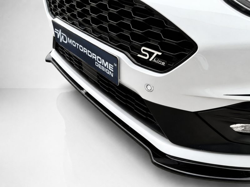 K182-001_4jpg - OPSHOLDERS Close-up of a white car front with a black honeycomb grille, featuring an ST Line badge and a blue plate with text.