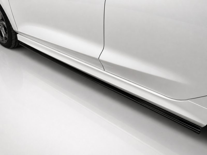 Side view of a white car showing the door seam and lower body panel with a side skirt running along the bottom edge