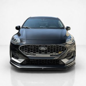 Front view of a black Ford sedan in a studio, featuring a honeycomb grille and Ford emblem
