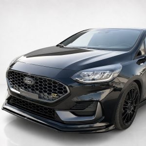 Front three-quarter view of a glossy black Ford car, showing honeycomb grille, prominent headlights, and side mirrors.