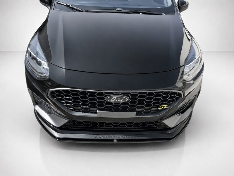 Front view of a dark gray Ford car, showing the bold honeycomb grille and Ford emblem.