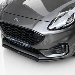Front view of a dark gray Ford car, featuring a honeycomb grille, headlight, and a MotorDrome Design plate.