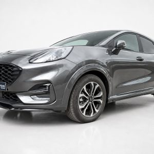 Gray crossover SUV in a studio setting, front-left three-quarter view highlighting the bold grille and alloy wheels.