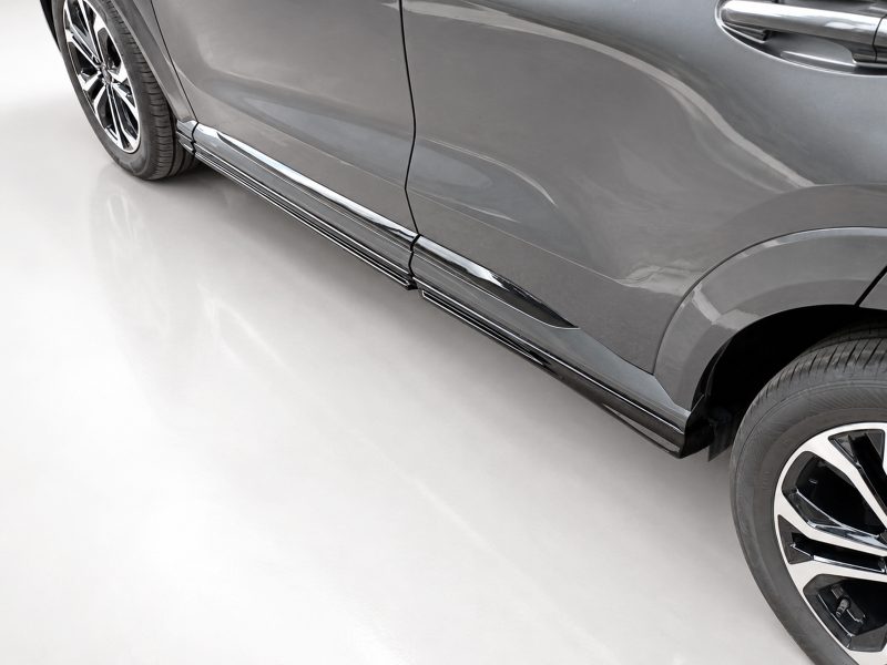 Close-up of a gray SUV showing chrome side steps along the lower body rimmed with shiny trim, photographed from the side.