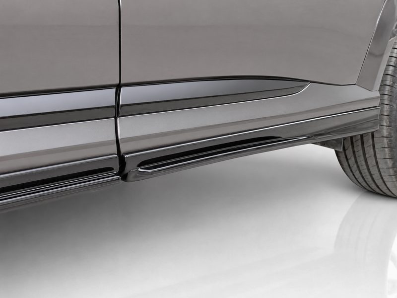 Close-up of a dark gray SUV's lower door panels with a chrome running board and tire visible on the right side.