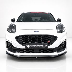 Front view of a white Ford car with a large hexagonal black grille and prominent headlights, featuring a MotorDrome Design plate at the bumper.