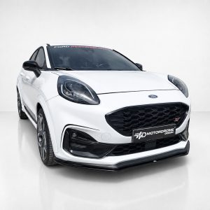 Front three-quarter view of a white Ford SUV in a studio, highlighting the black honeycomb grille and bold headlights.