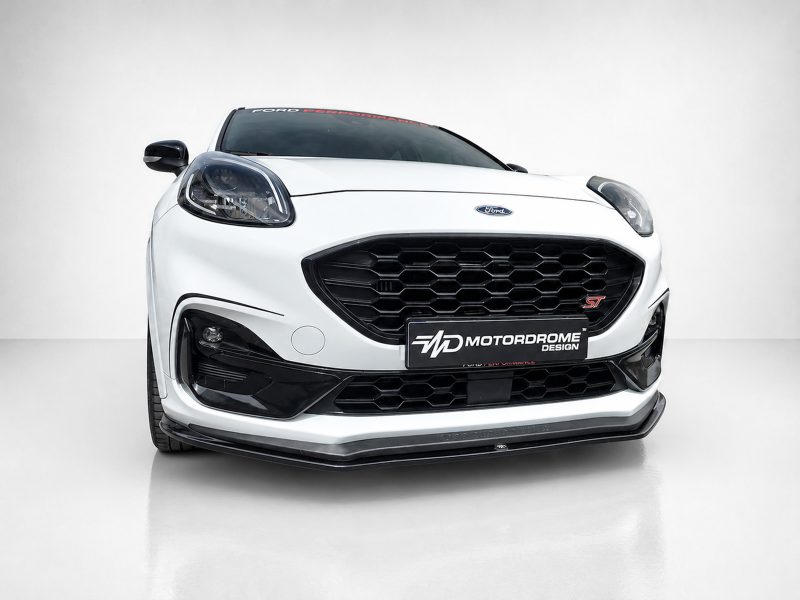Front view of a white Ford car with a large black honeycomb grille and ST badge in a studio setting, Motordrome Design plate visible on the bumper.
