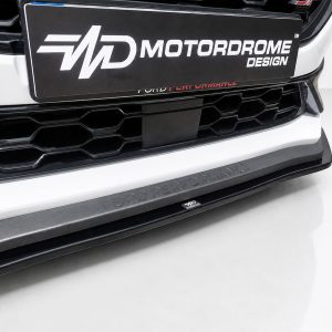 Front bumper close-up of a white Ford with a honeycomb grille and a Ford Performance lip plate reading 'FORD PERFORMANCE' (car show/photo set).