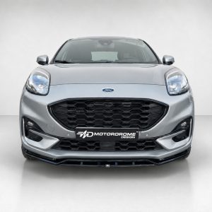 Front view of a silver Ford car with a large black honeycomb grille and distinctive rounded headlights.