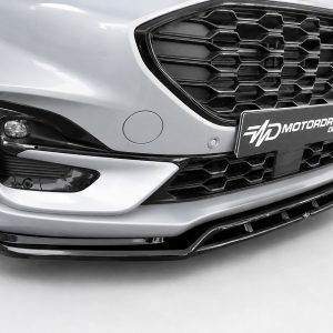 Close-up of a silver car's front end with a honeycomb grille, left headlight, and a MOTORDROME DESIGN license plate caping the front bumper.