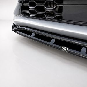 Close-up of a car's front bumper and grille, featuring chrome trim and a small MD badge on the lower grille.