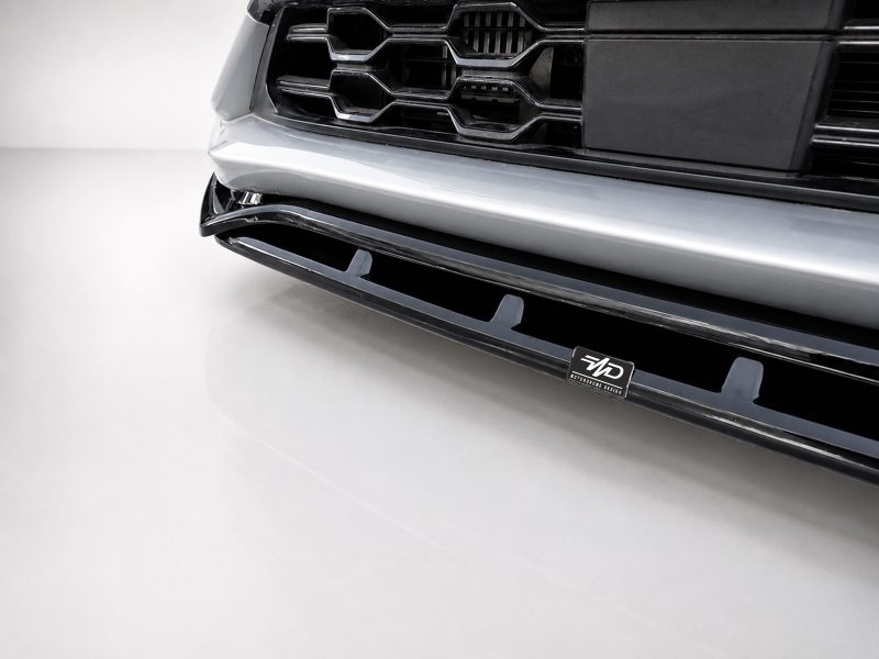 Close-up of a car's front bumper and grille, featuring chrome trim and a small MD badge on the lower grille.