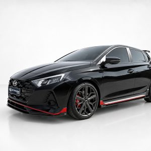 Front three-quarter view of a glossy black sports hatchback with red side skirts and large multi-spoke wheels.