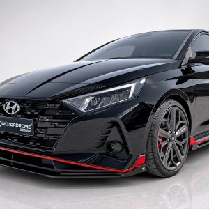 Black sports sedan, close-up front-left angle showing sleek grille, angular headlights, and red accent trim along the bumper and side skirts.