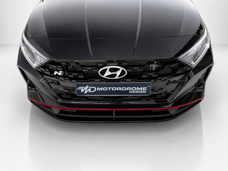 Front view of a glossy black Hyundai with a large grille, Hyundai emblem center, N badge on the left, and a red accent line along the lower bumper; license plate reads MOTORDROME DESIGN.
