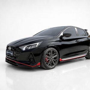 Glossy black Hyundai hatchback with red accents and large alloy wheels in a white studio setting