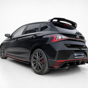 Black Hyundai hatchback with red racing accents and a large rear spoiler photographed in a studio.