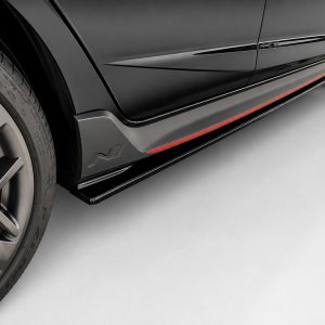 Close-up of a black sports car's lower side panel with a red accent stripe and a large alloy wheel visible on the left.