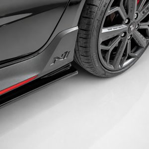 Close-up of a black sports car’s side panel and alloy wheel, with a red accent stripe along the rocker.
