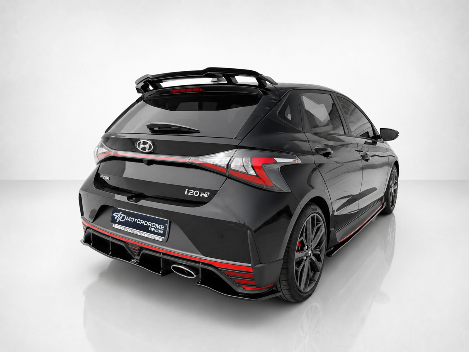 K185-003_1jpg - OPSHOLDERS Black Hyundai i20 N hatchback shown from rear three-quarter view with red accents and a roof spoiler, indoors