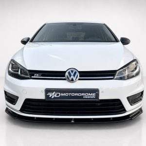 Front view of a white Volkswagen car with the emblem, grille, and headlights visible in a studio setting, Motordrome Design plate
