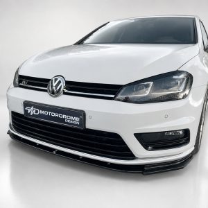 Front view of a white Volkswagen sedan with black grille and emblem on a showroom floor
