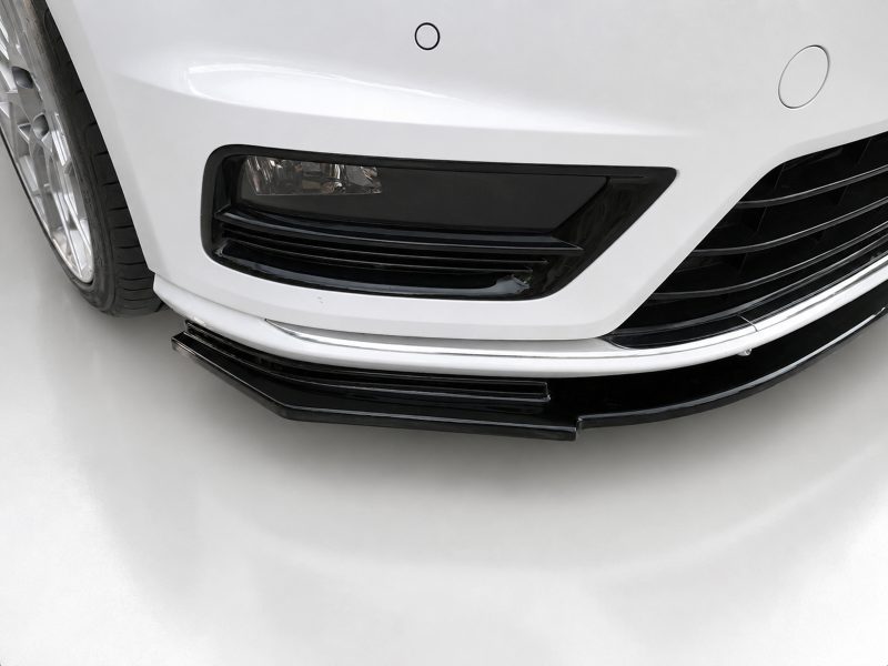 Front lower section of a white car showing a black grille, bumper lip, and chrome accent near the ground, with a tire visible on the left.