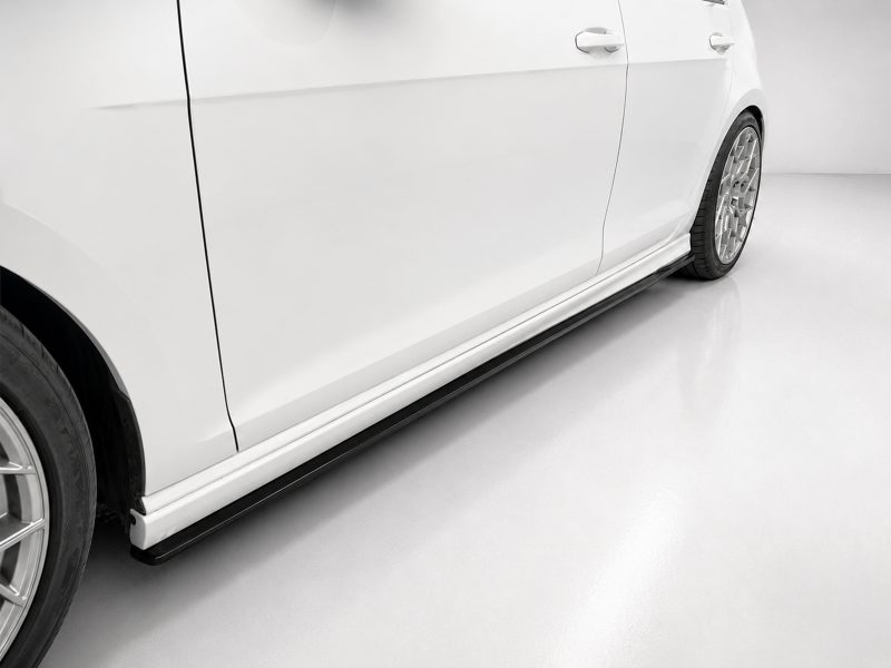 Side view of a white car with alloy wheels and a black side step visible along the lower body edge.