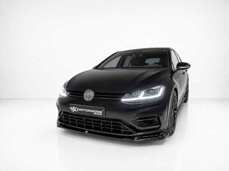 Black sport sedan shown in a three-quarter front view on a white studio backdrop, with a Motordrome Design plate on the bumper