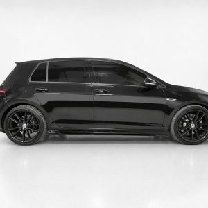 Side profile of a black SUV/hatchback with tinted windows and large black alloy wheels inside a studio setting