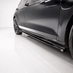 Close-up of a glossy dark car's side profile, featuring a low side skirt and alloy wheel with a Continental tire on a light showroom floor.