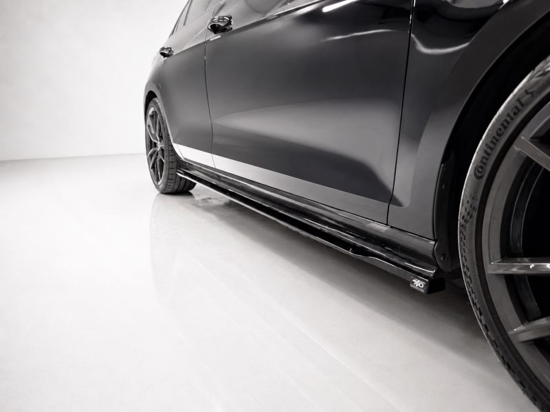 Close-up of a glossy dark car's side profile, featuring a low side skirt and alloy wheel with a Continental tire on a light showroom floor.