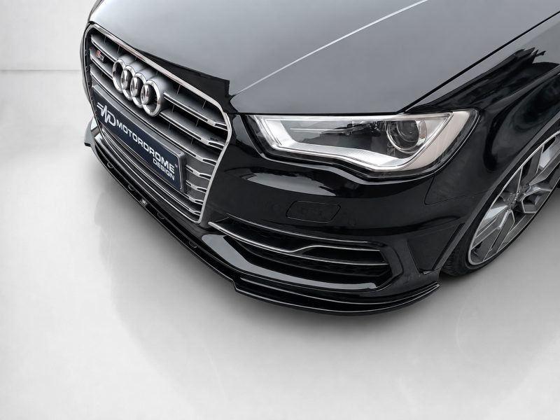 Front close-up of a glossy black Audi with the chrome grille, four-ring emblem, and sleek headlight visible.