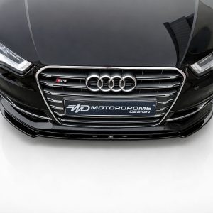 Front view of a black Audi car showing the four-ring emblem and S3 badge on a chrome grille, with headlights visible on either side corporate lighting.