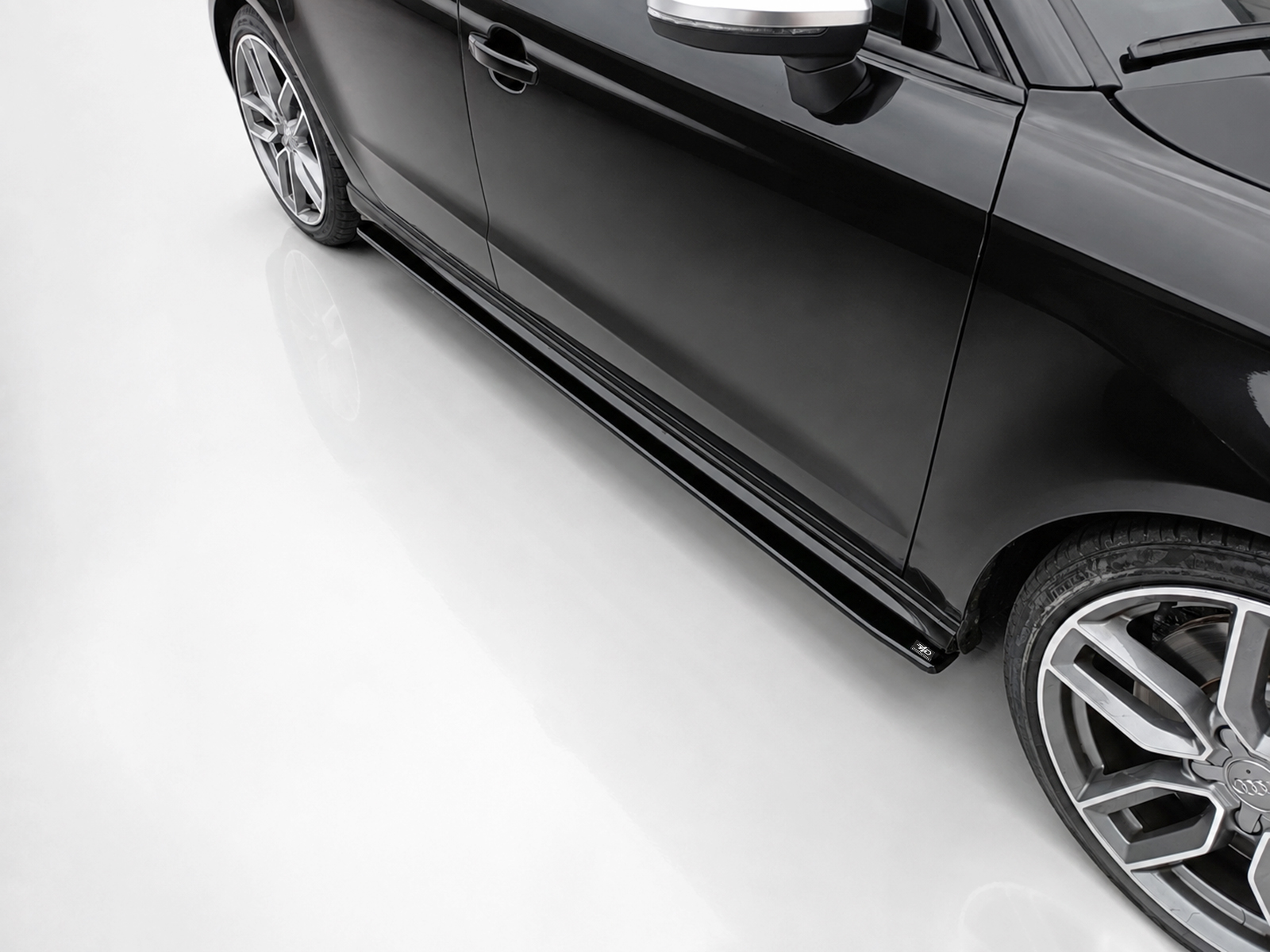 K187-002_2jpg - OPSHOLDERS Close-up of a sleek black car's lower side and alloy wheel, highlighting the side skirt and glossy finish.