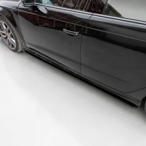 K187-002_3jpg - OPSHOLDERS Side view of a sleek black car showing the door, handle, and running board with alloy wheels in a studio setting.