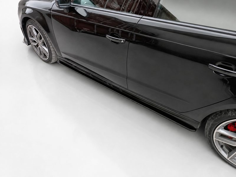 K187-002_3jpg - OPSHOLDERS Side view of a sleek black car showing the door, handle, and running board with alloy wheels in a studio setting.